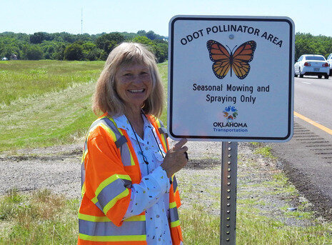 Vonceil Harmon with ODOT stands next to a roadside pollinator sign.